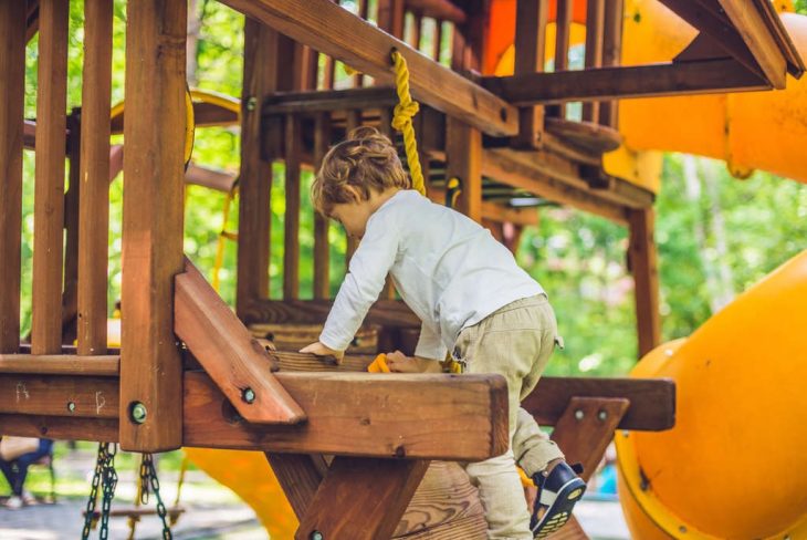 menino se divertindo em casinha de madeira playground para crianças