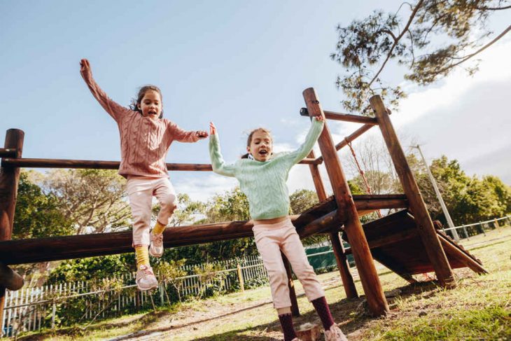 meninas se divertindo em ponte pênsil de madeira em playground para crianças